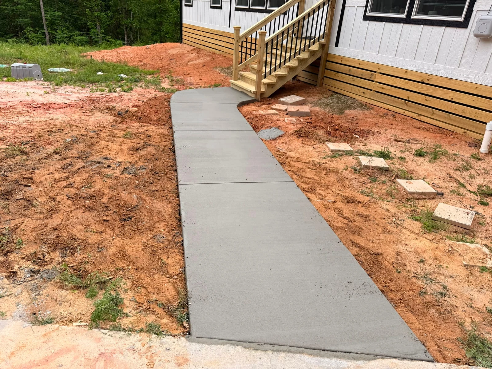 A concrete walkway running between a driveway and a house